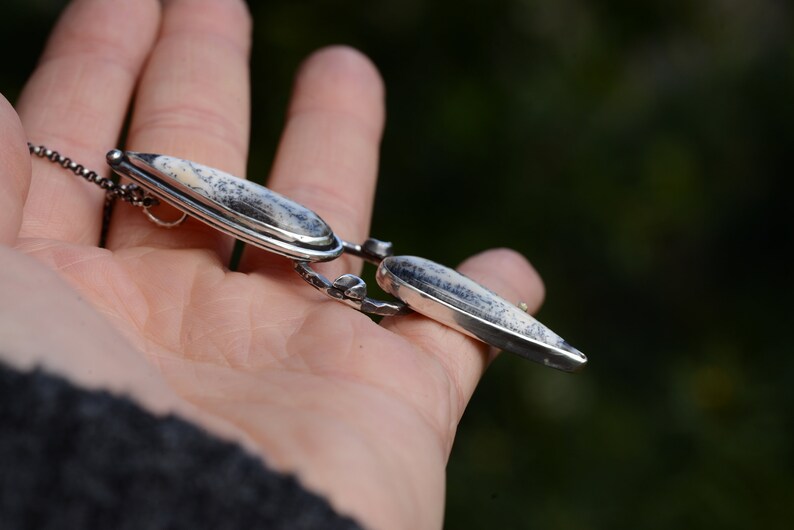 May include: A silver necklace with a pendant featuring two white and gray agate stones set in silver.