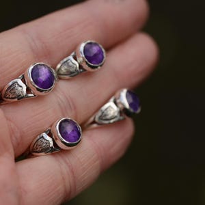 May include: Four silver rings featuring purple amethyst gemstones. The rings have a delicate design with a wing-like detail on the band.