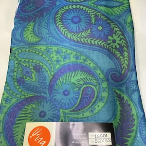 May include: A rectangular fabric piece featuring a vibrant paisley pattern in shades of blue, purple, and green. A white label at the bottom displays the text "Vera", "easy-to-care-for", "screen-printed", "all belgian linen", "style 18801", and "size 52X52".