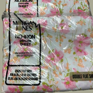 Puede incluir: Dos paquetes de sábanas planas de percal Morgan Jones sin planchado con fondo blanco y estampado floral rosa y naranja. El empaque indica 50% poliéster Dacron y 50% algodón, para un colchón de 137 cm por 193 cm, 206 por 264 cm antes del dobladillo.