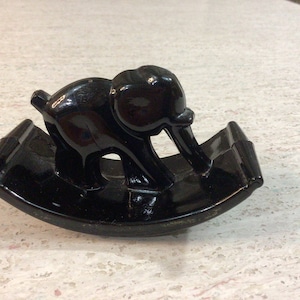 May include: A black ceramic rocking elephant figurine. The elephant is in a rocking motion and has a glossy finish.
