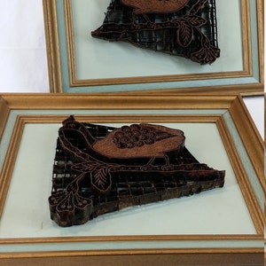 May include: Two framed woodblock printing stamps, each depicting a bird with intricate details. The stamps are brown and black, and are set against a light blue background.