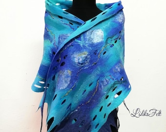 Può includere: Un scialle in feltro di lana blu e turchese con disegni ritagliati. Lo scialle presenta un gradiente di colore dal blu scuro al turchese chiaro. Lo scialle è drappeggiato su un manichino.