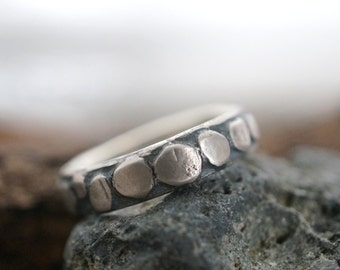 Puede incluir: Un anillo de plata con una banda texturizada y una fila de acentos redondos de plata en relieve.