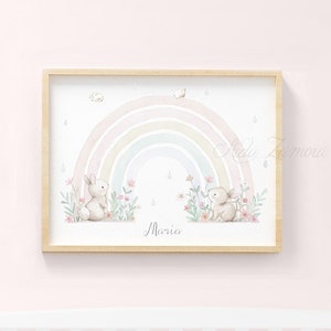 Peut inclure: Une impression murale horizontale encadr&eacute;e pr&eacute;sentant une illustration &agrave; l'aquarelle de deux petits lapins assis dans un champ de fleurs roses sous un arc-en-ciel pastel avec des gouttes de pluie. Le pr&eacute;nom Maria est &eacute;crit en cursif en bas.