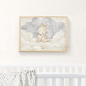 May include: A framed watercolor print featuring a large beige rabbit hugging a smaller beige rabbit. They are sitting on fluffy white clouds against a dark gray sky filled with small white stars. The signature Aida Zamora is visible.