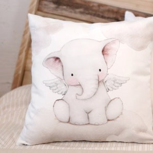 Peut inclure: Un coussin carr&eacute; orn&eacute; d'une illustration &agrave; l'aquarelle d'un &eacute;l&eacute;phanteau blanc avec de petites ailes d'ange, assis sur un nuage. L'&eacute;l&eacute;phant a des joues roses et des yeux noirs, sur un fond blanc avec des nuages l&eacute;gers en arri&egrave;re-plan.