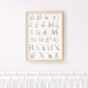 May include: A framed alphabet poster with a white background and brown frame. Each letter of the alphabet is displayed in a large, white font with a different animal illustration next to each letter. The animals are drawn in a watercolor style with muted colors.