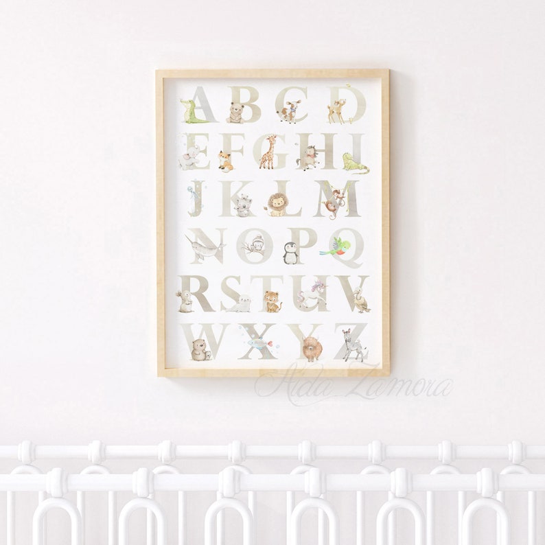 May include: A framed alphabet poster with a white background and brown frame. Each letter of the alphabet is displayed in a large, white font with a different animal illustration next to each letter. The animals are drawn in a watercolor style with muted colors.