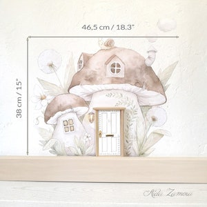 Peut inclure: Un autocollant mural repr&eacute;sentant deux maisons champignons brunes avec des fen&ecirc;tres, un escargot sur le toit et du feuillage. Une petite porte blanche est plac&eacute;e devant. Les dimensions sont 46,5 cm sur 38 cm. Le texte Aida Zamora est visible.