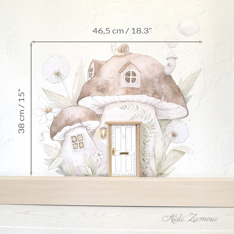 Peut inclure: Un autocollant mural repr&eacute;sentant deux maisons champignons brunes avec des fen&ecirc;tres, un escargot sur le toit et du feuillage. Une petite porte blanche est plac&eacute;e devant. Les dimensions sont 46,5 cm sur 38 cm. Le texte Aida Zamora est visible.