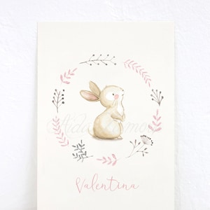 Pu&ograve; includere: Un'illustrazione ad acquerello di un coniglio marrone in piedi in una ghirlanda floreale rosa e grigia. Il nome "Valentina" &egrave; scritto in rosa sotto la ghirlanda.