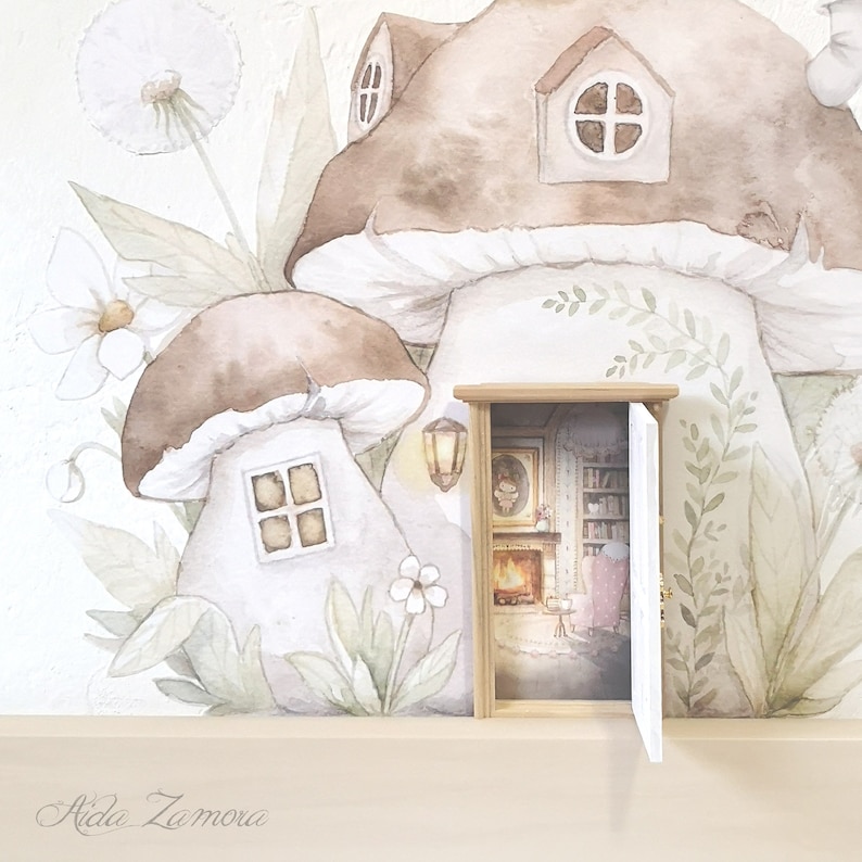 Peut inclure: Un autocollant mural repr&eacute;sentant des champignons &agrave; l'aquarelle avec des fen&ecirc;tres et une petite porte en bois en trois dimensions qui s'ouvre sur une sc&egrave;ne int&eacute;rieure avec chemin&eacute;e, biblioth&egrave;que et fauteuil. Le texte Aida Zamora est imprim&eacute; en bas.