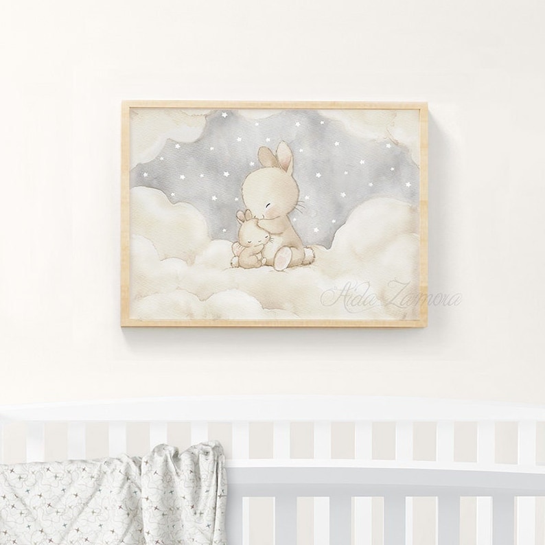 May include: A framed watercolor print featuring a large beige rabbit hugging a smaller beige rabbit. They are sitting on fluffy white clouds against a dark gray sky filled with small white stars. The signature Aida Zamora is visible.