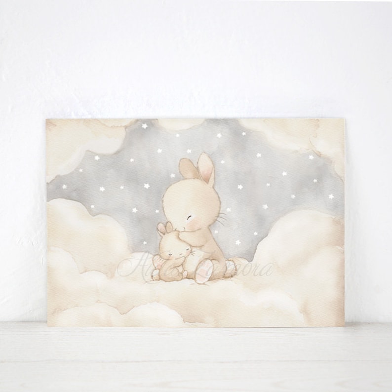 May include: A rectangular wall art print featuring a watercolor illustration of two beige rabbits sitting together on soft, fluffy clouds. The background shows a gray night sky filled with small white stars, creating a gentle and calm scene.