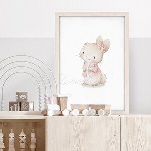 K&ouml;nnte beinhalten: Eine Aquarell-Illustration eines niedlichen Kaninchens, das eine rosa Jacke und eine rosa Schleife tr&auml;gt. Das Kaninchen steht auf einem wei&szlig;en Hintergrund.
