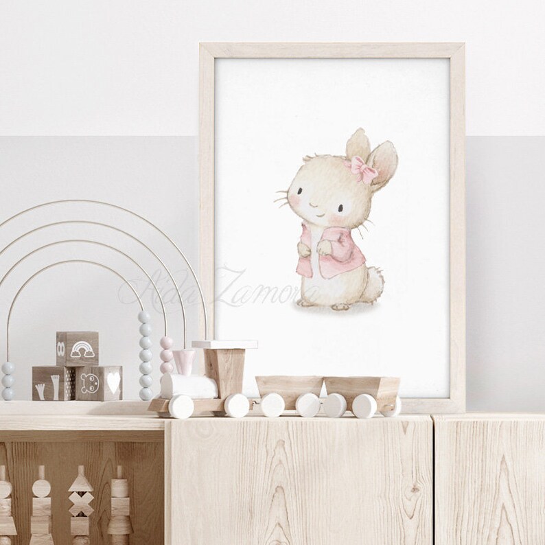 K&ouml;nnte beinhalten: Eine Aquarell-Illustration eines niedlichen Kaninchens, das eine rosa Jacke und eine rosa Schleife tr&auml;gt. Das Kaninchen steht auf einem wei&szlig;en Hintergrund.