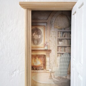 Peut inclure: Un cadre de porte miniature en bois s'ouvrant sur une illustration d&eacute;taill&eacute;e d'une pi&egrave;ce chaleureuse avec une chemin&eacute;e, une biblioth&egrave;que, un fauteuil &agrave; carreaux, une petite table ronde et un portrait de souris encadr&eacute; au mur.