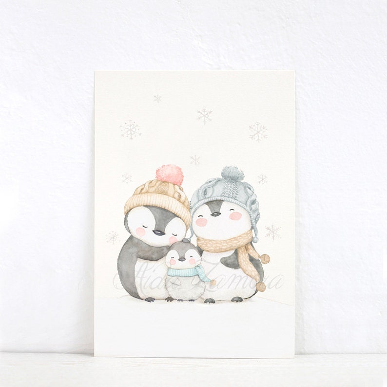 May include: A watercolour illustration of a penguin family consisting of two adults and one chick standing together. The penguins wear knit hats and scarves in shades of beige, grey, and blue. The background is white with light grey snowflakes.