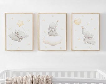 May include: Three framed wall art prints featuring watercolor illustrations of gray elephants with small white wings. The elephants are depicted among yellow stars, clouds, and a moon on a white background, displayed in light wood frames.