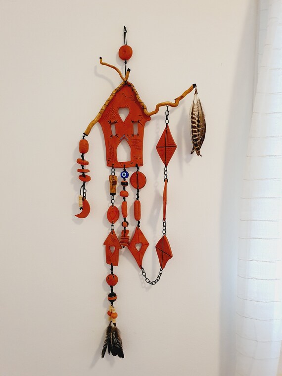 Handmade ceramic house sculpture with actual feathers incorporated — a genuinely weird, one-of-a-kind wall piece that straddles art and craft in the best way.