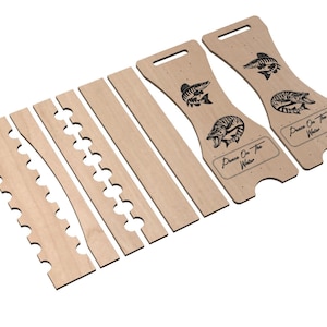 May include: A wooden fishing rod holder with a cutout design and the text "Peace On The Water". The holder is made of light brown wood and has a natural finish.