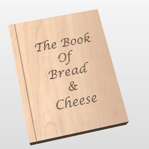 May include: A wooden book with the title "The Book Of Bread & Cheese" engraved on the cover. The book is light brown with a dark brown spine. The text is in a serif font.