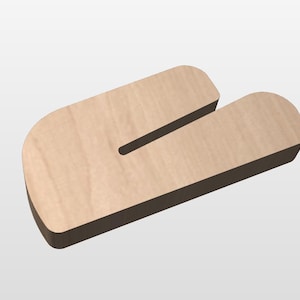 Peut inclure: Un organiseur de bureau en bois clair avec une découpe en forme de U. L'organisateur a des coins arrondis et un bord marron foncé, créant un effet tridimensionnel. Le grain du bois est visible.