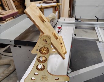Puede incluir: Un soporte de madera con una parte superior inclinable, diseñado para sostener un portátil o una tableta. El soporte tiene un diseño único con múltiples recortes circulares y un patrón de engranaje.