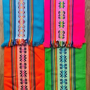 Puede incluir: Cuatro manteles individuales tejidos con flecos. Los manteles individuales son de colores brillantes: turquesa, rosa, naranja y verde. Cada mantel individual tiene un patrón geométrico diferente en el centro.