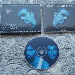 May include: A collection of George Michael memorabilia, including a CD and two book-style cases. The CD features two portraits of George Michael in blue tones. The cases display George Michael's portrait and text, including "The Unauthorised Edition."
