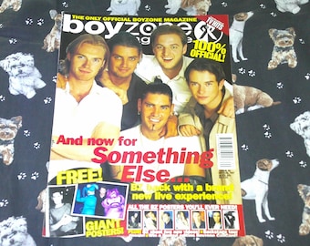 May include: A Boyzone magazine cover featuring five men, with the text "And now for Something Else" in red and white. The magazine is on a black fabric with dog illustrations.