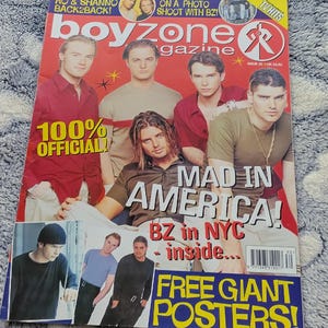 May include: A magazine cover featuring the band Boyzone, with the title "boyzone magazine" in large letters. The cover includes the text "MAD IN AMERICA!" and "FREE GIANT POSTERS!" The magazine is set against a patterned background.