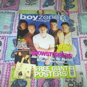 May include: A magazine cover for Boyzone, featuring six men. The magazine is titled "boyzone maga" and includes text such as "Showstoppers!" and "Free Giant Posters!" The cover is on a patterned fabric.