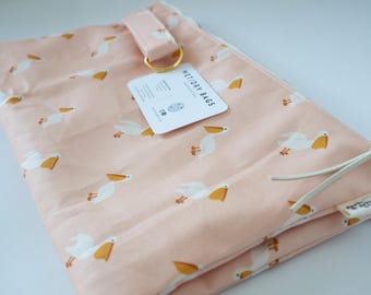 May include: A light pink wet/dry bag featuring a repeating pattern of white pelicans with yellow beaks. The bag includes a gold-toned metal D-ring, a white zipper pull, and a white product tag with the text WET/DRY BAGS printed in black ink.