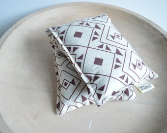 May include: A rectangular fabric pillow featuring a cream-colored base with a repeating dark brown geometric pattern of squares and triangles. A small white fabric tag with the text "fork & arrow" is attached to the side of the pillow.