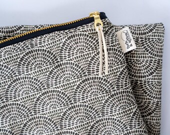 May include: A fabric pouch featuring a repeating black and white fan-shaped pattern. The pouch has a dark blue zipper with a gold-toned metal pull and two thin white cord pulls. A small white fabric tag with the text fern & arrow is attached.