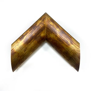 May include: A corner of a gold picture frame with a wood grain texture.