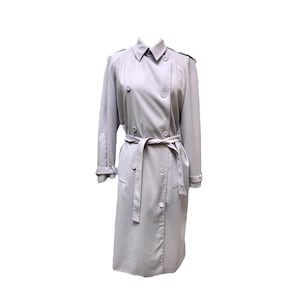 May include: A light gray trench coat with a double-breasted design. The coat features a belted waist, a classic collar, and button closures. The sleeves are long with buttoned cuffs. A timeless outerwear piece.