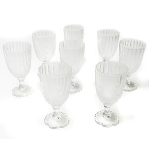 Puede incluir: Un conjunto de ocho copas de vino transparentes y esmeriladas. Cada copa presenta un diseño texturizado de rayas verticales en el cuenco y una base festoneada. Las copas están dispuestas sobre una superficie blanca.