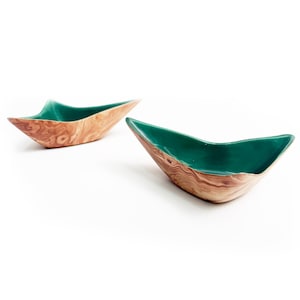 May include: Two wooden bowls in a boat shape. The exterior has a natural wood grain, and the interior is a glossy, deep green. The bowls are set against a white background. The bowls are likely for decorative purposes.