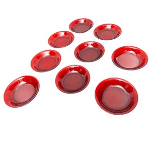 Può includere: Set di dieci piatti da dessert in vetro rosso. I piatti sono rotondi e hanno un bordo leggermente rialzato.