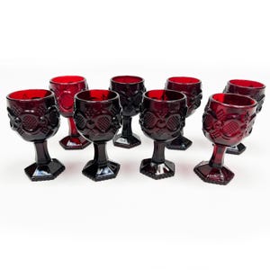 Pode incluir: Conjunto de oito taças de vidro vermelho-rubi com um design texturizado. As taças têm uma tigela redonda e uma base hexagonal.