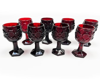 May include: Set of eight ruby red glass goblets with a textured design. The goblets have a round bowl and a hexagonal base.