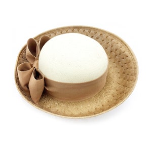 May include: A straw hat with a wide brim and a brown ribbon tied in a bow. The hat is made of a woven material and has a light brown colour.