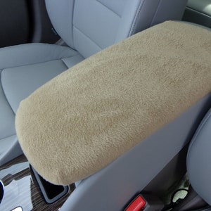 May include: Beige fleece car armrest cover for added comfort and protection.