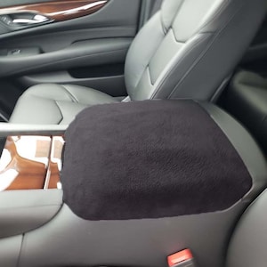 May include: Black car seat armrest cover with a soft, plush texture. The cover is designed to protect the armrest from wear and tear.