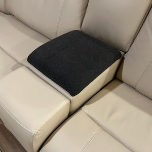 May include: A white leather sofa with a black fabric armrest cushion.