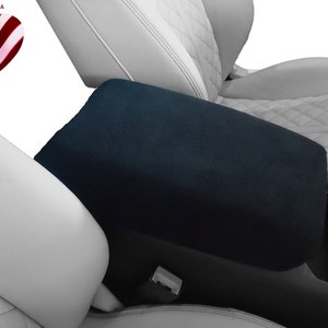 May include: Black armrest cover for a car seat. The cover is made of a soft, plush material and is designed to protect the armrest from wear and tear.