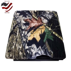 May include: Camouflage fabric seat cover with a black background and brown, green, and yellow leaves. The fabric has a soft, fuzzy texture.